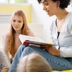 Ensino, Educadora em sala a ler uma história com duas crianças a escutar